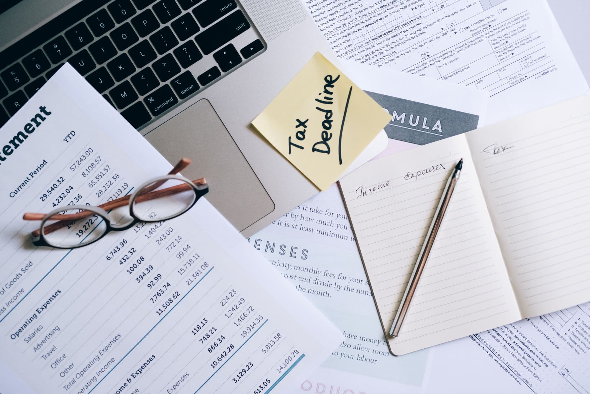 Printed financial statements on a desk with glasses and a notebook