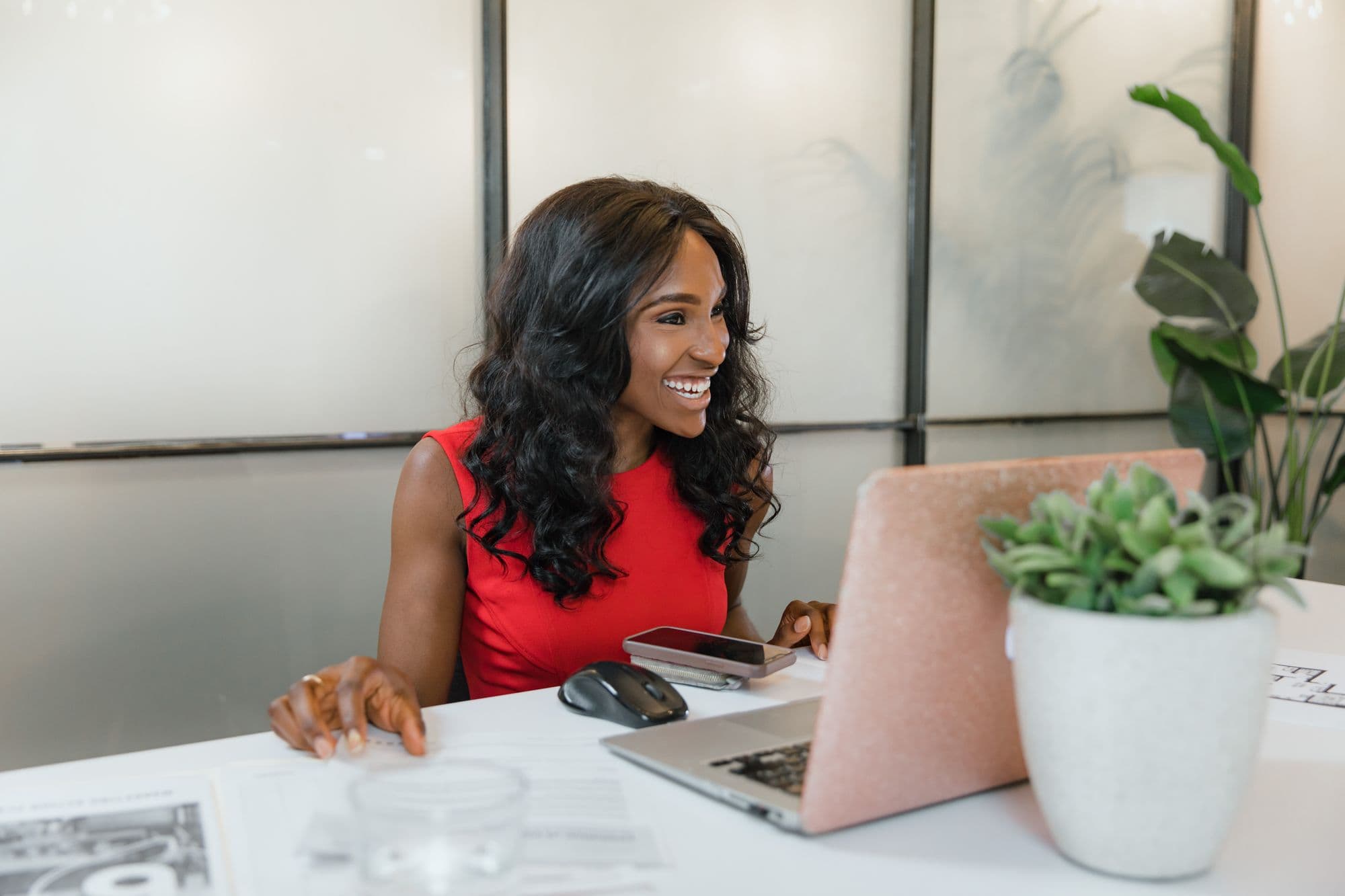 Business owner smiling at her laptop in a bright office